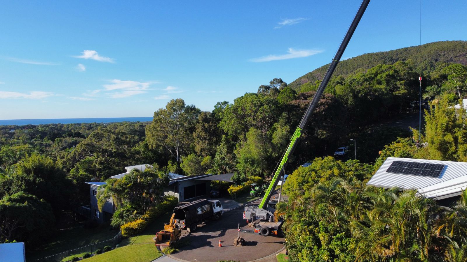 Summit Tree Services crane working above homes on the Sunshine Coast
